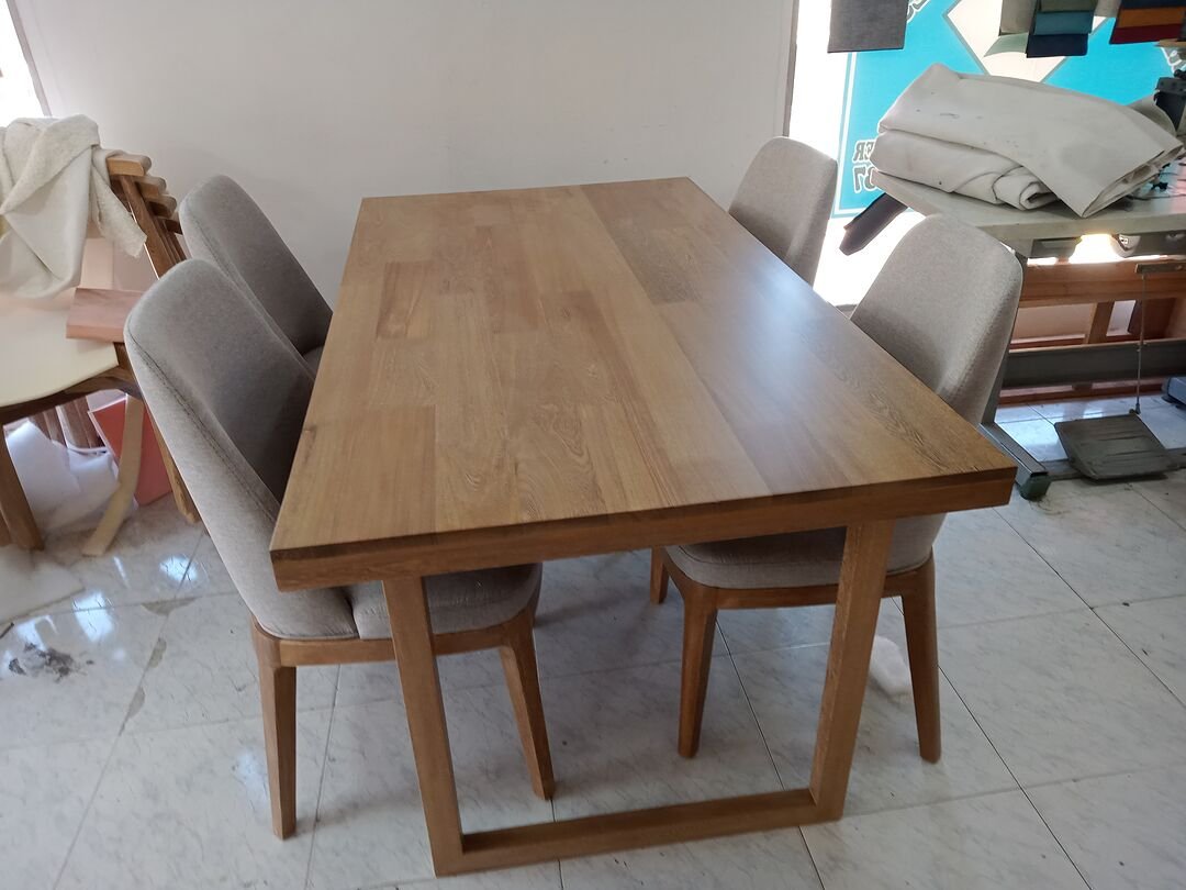 Comedor a medida con mesa de madera y cuatro sillas tapizadas en tela gris claro, fabricado en nuestro taller de Bogotá