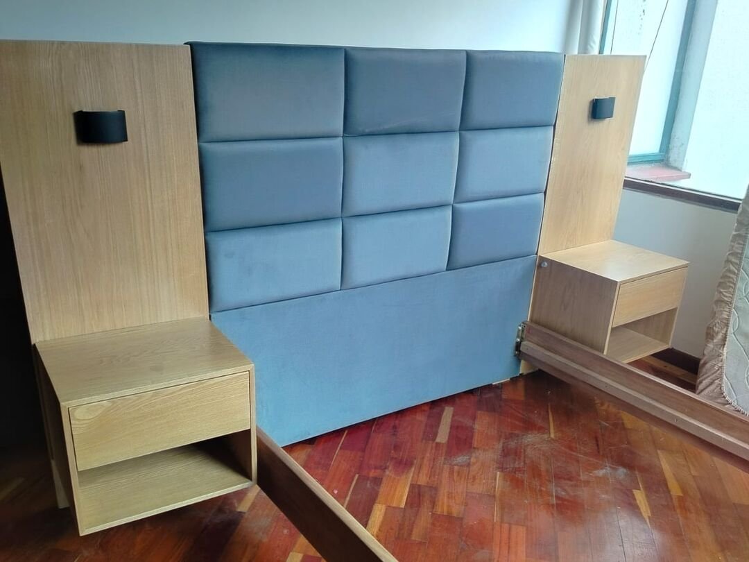 Espaldar de cama tapizado en paneles azules con mesas de noche de madera integradas, hecho a la medida en nuestro taller de Bogotá